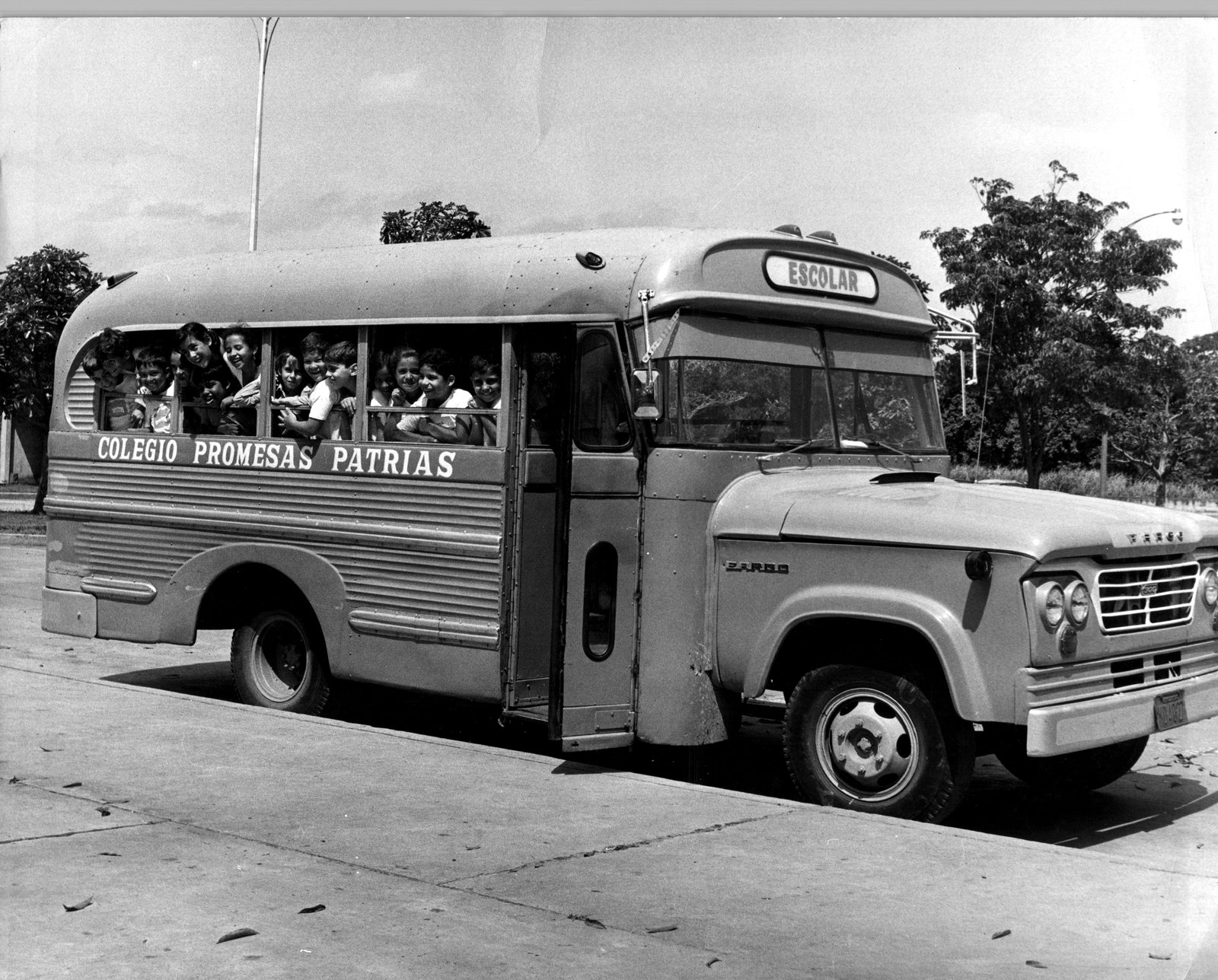 Autobús escolar histórico del Colegio Promesas Patrias con estudiantes asomados a las ventanas
