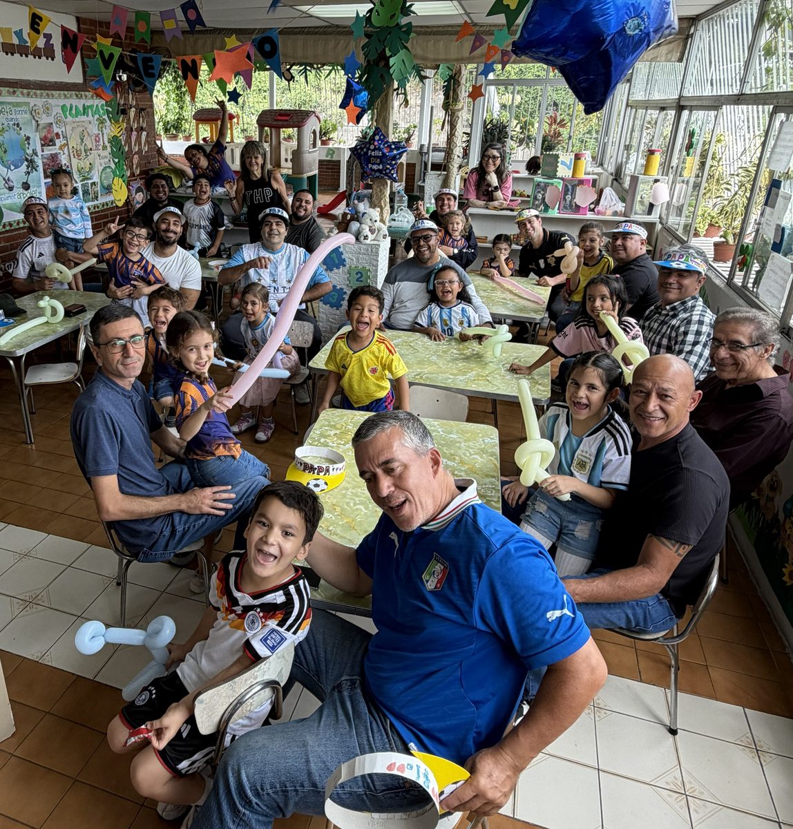 Papás celebrando el Día del Padre junto a sus hijos en un salón del colegio